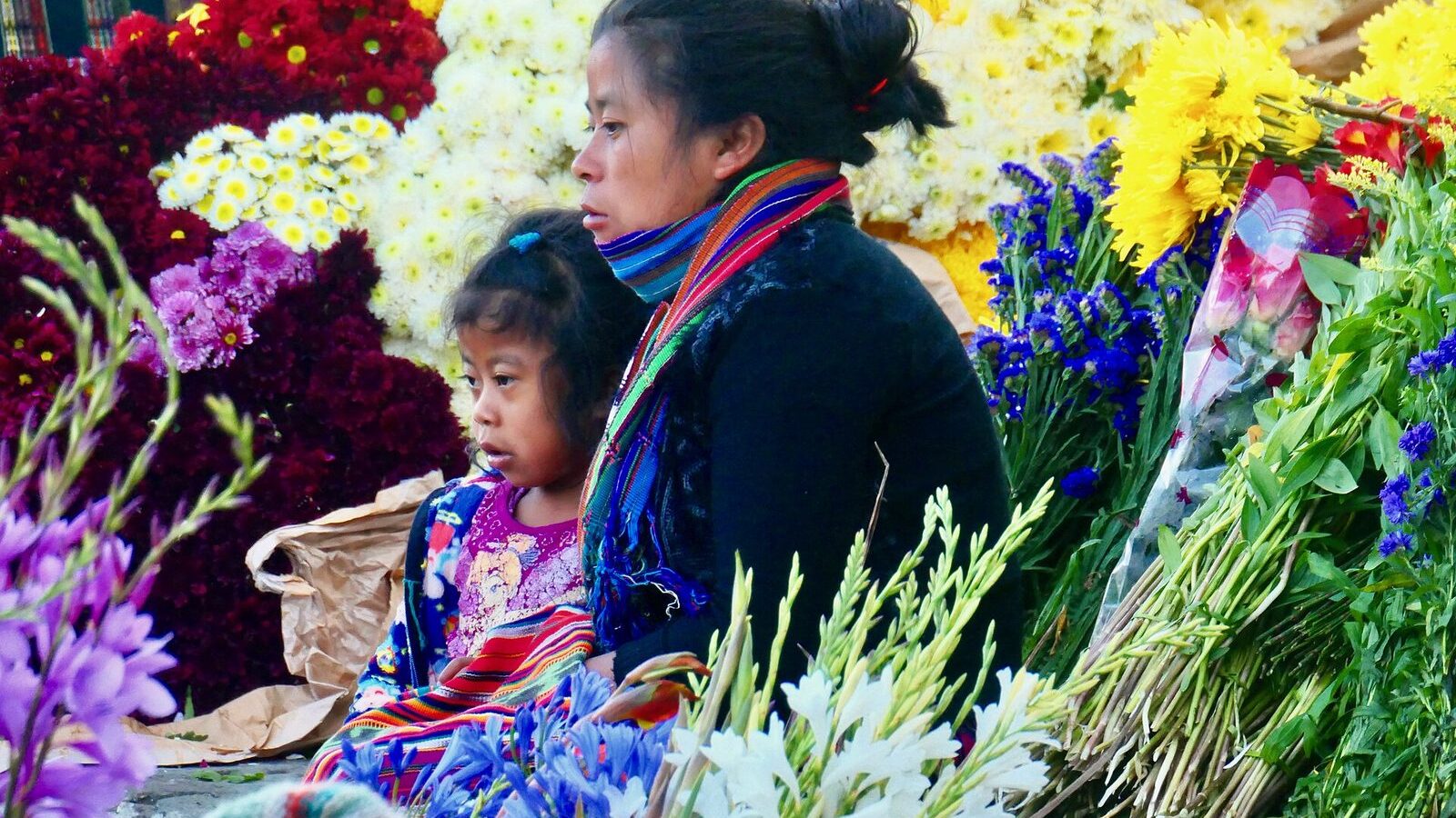 Puesto de flores del mercado de Chichicastenango con vendedoras vestidas con huipiles