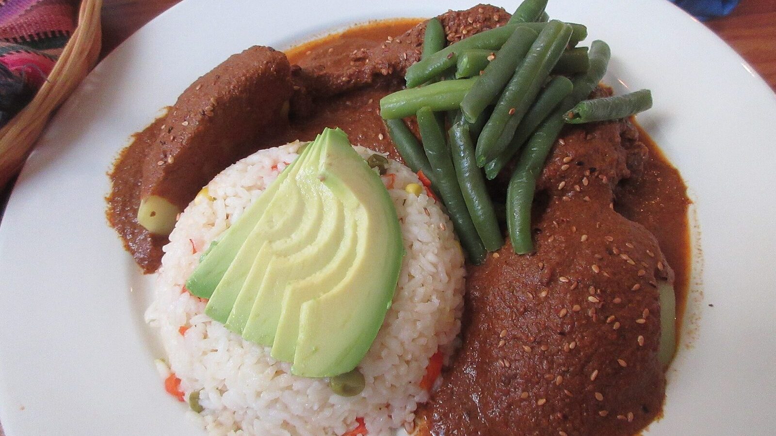 Plato de pepián guatemalteco con arroz, aguacate y judías verdes