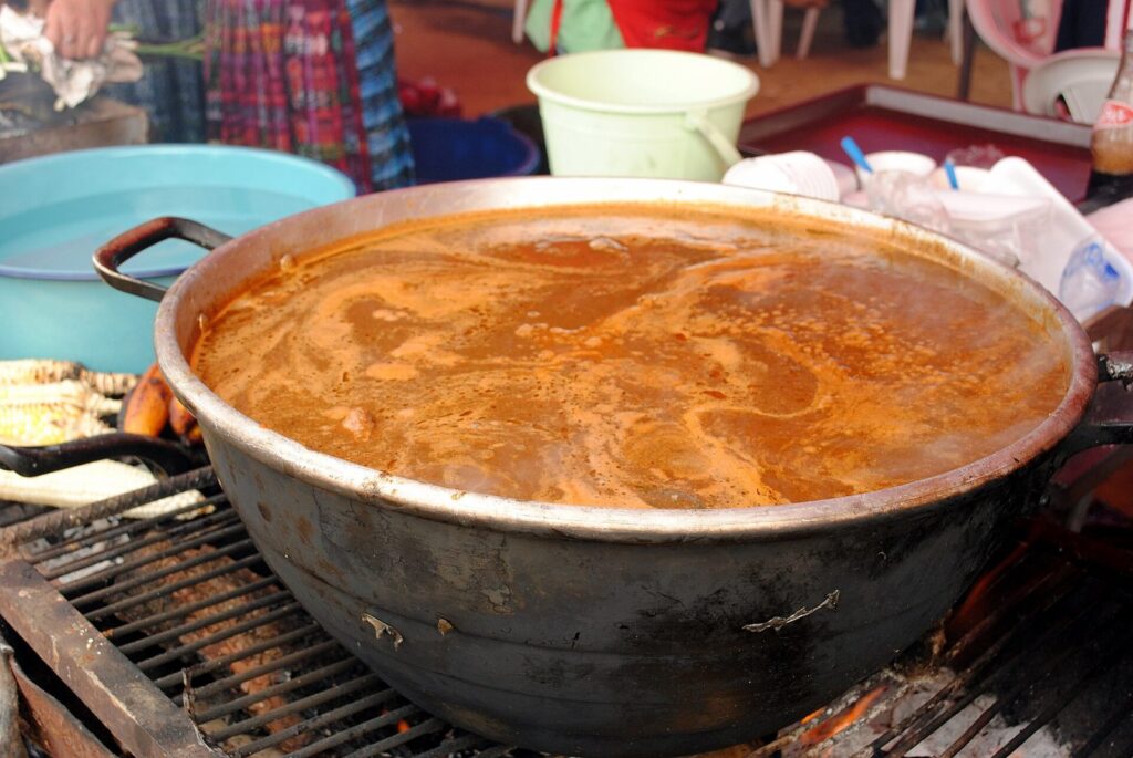 Olla de barro con pepián cocinándose sobre el fuego
