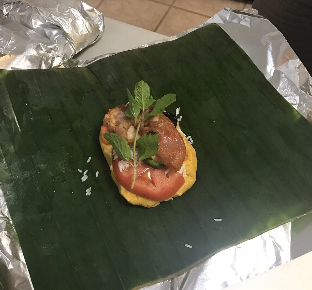 Nacatamal abierto sobre su hoja de plátano mostrando el relleno de masa y carne