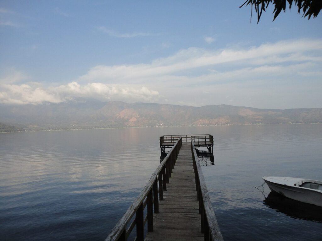 Muelle de madera adentrándose en el lago de Coatepeque al atardecer
