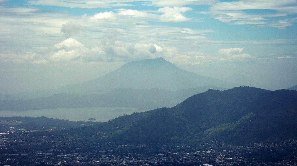 Volcán salvadoreño alzándose sobre la ciudad entre nubes