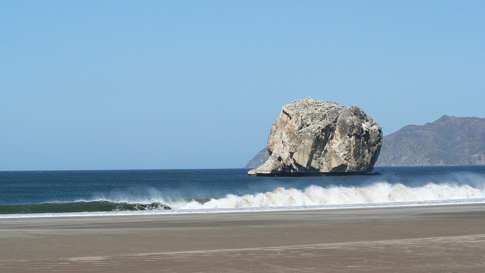 Roca Bruja emergiendo del mar frente a una playa de Guanacaste, Costa Rica