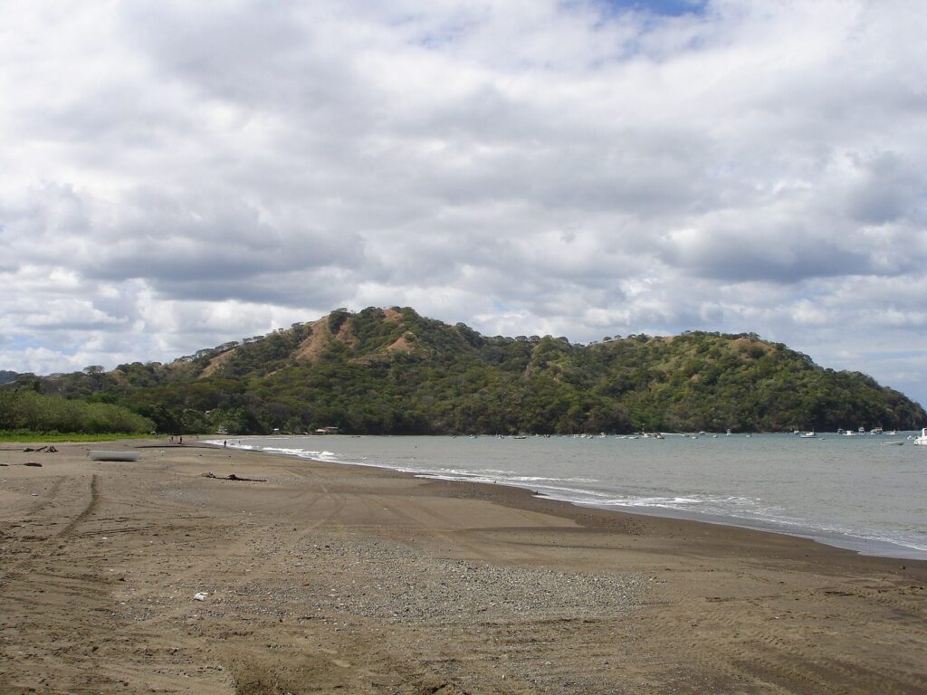 Playa del Pacífico costarricense con una colina boscosa al fondo