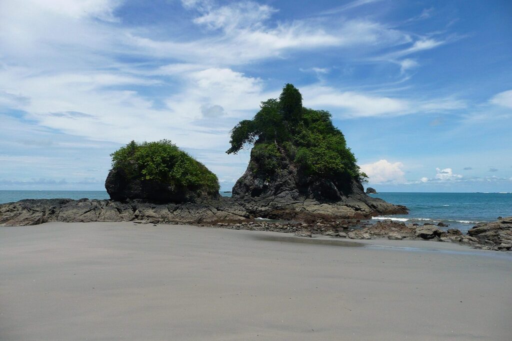 Formación rocosa cubierta de vegetación sobre la playa de Manuel Antonio