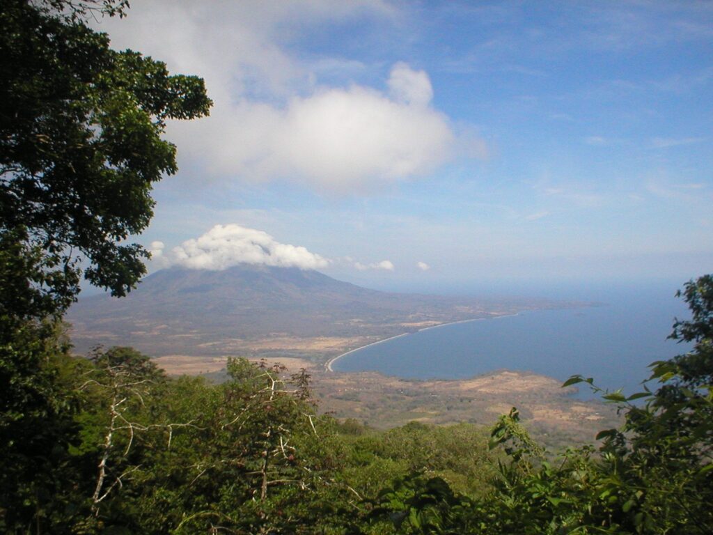 Vista del lago Nicaragua con un volcán al fondo desde una ladera boscosa