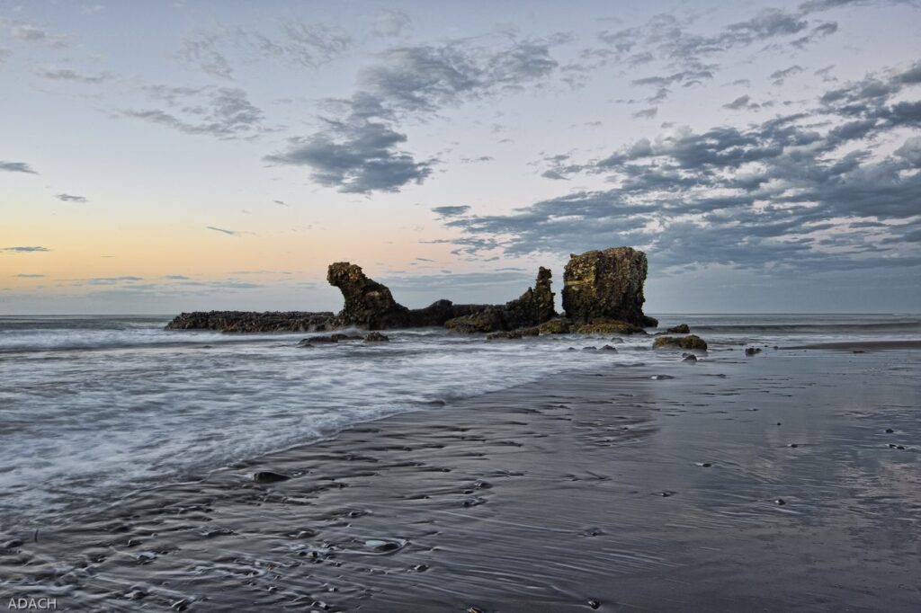 Rocas oscuras sobre la arena de una playa de surf de El Salvador