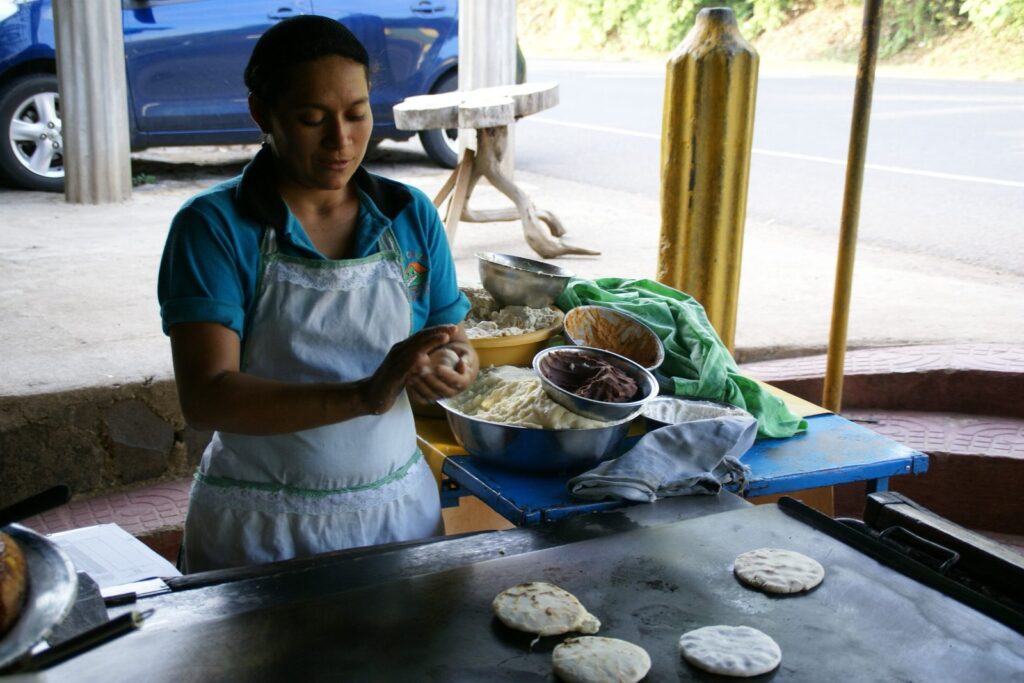 Cocinera dando forma a mano a las pupusas en una pupusería de El Salvador