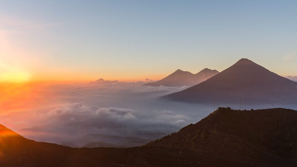 Siluetas de los volcanes guatemaltecos recortadas contra el cielo naranja del amanecer