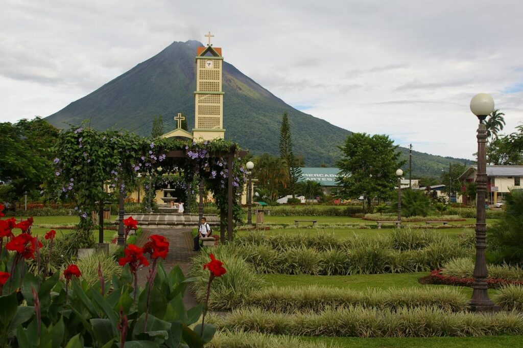Jardines con flores rojas y el volcán Arenal al fondo