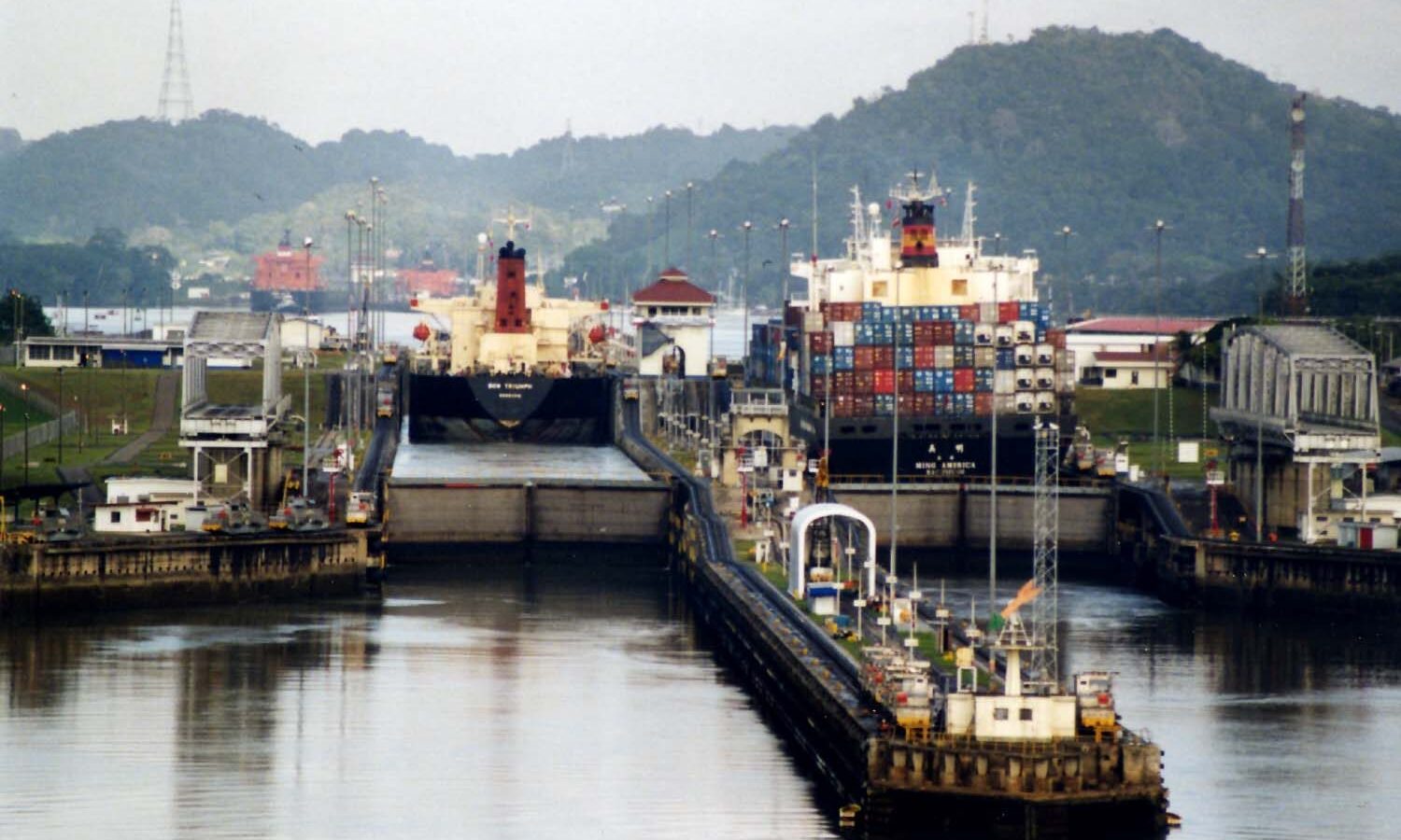 Buque de carga atravesando las esclusas del Canal de Panamá entre colinas verdes