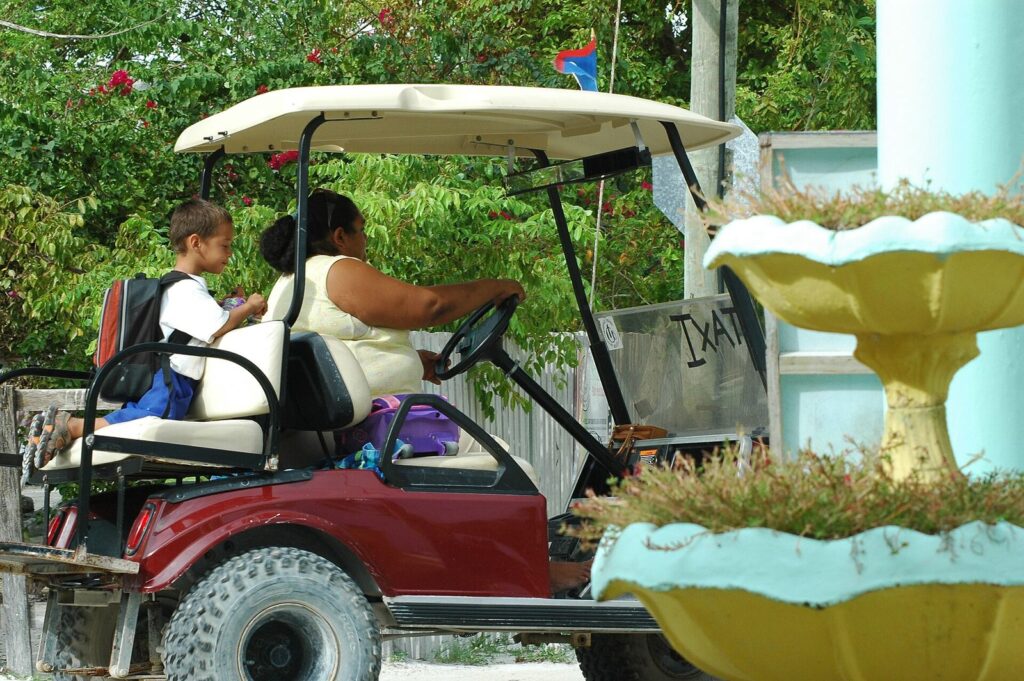 Carrito de golf circulando por una calle de arena de Caye Caulker