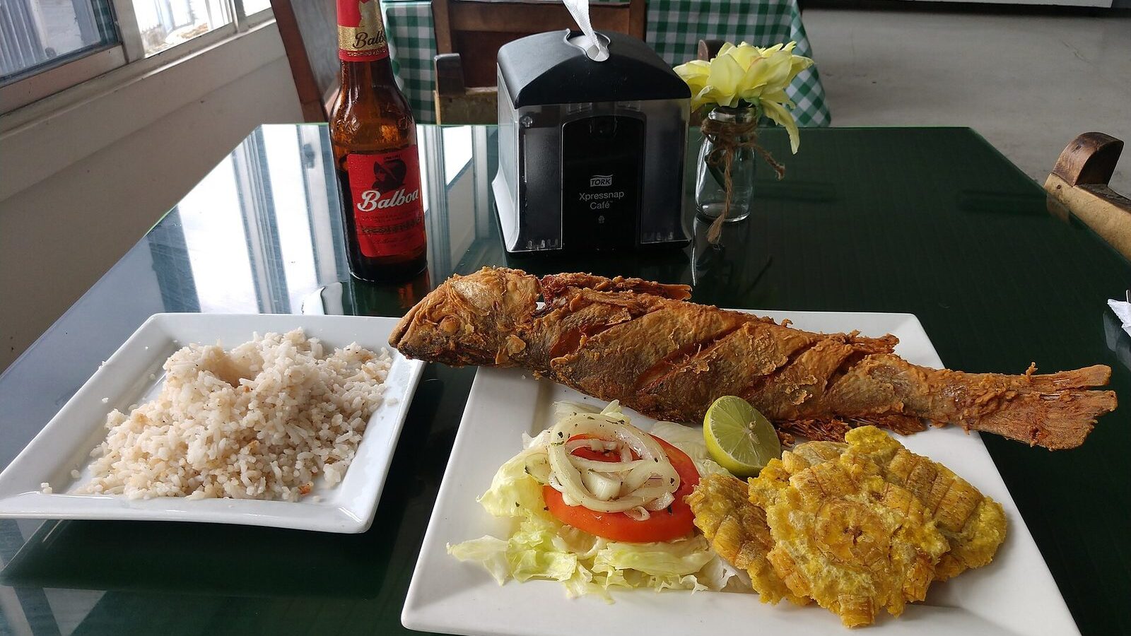 Pescado frito entero servido con arroz con coco y patacones